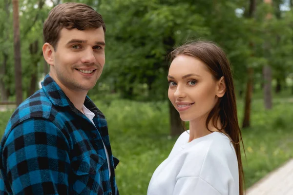 Namorado bonito e namorada bonita olhando para a câmera no parque — Fotografia de Stock