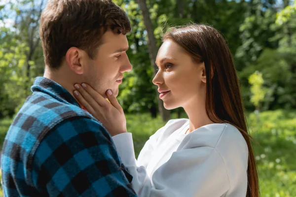 Side view of attractive girl touching face of handsome boyfriend in park — Stock Photo