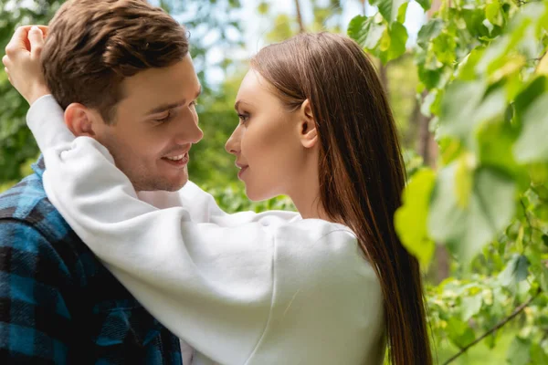 Selective focus of happy girl and smiling man hugging in park — Stock Photo