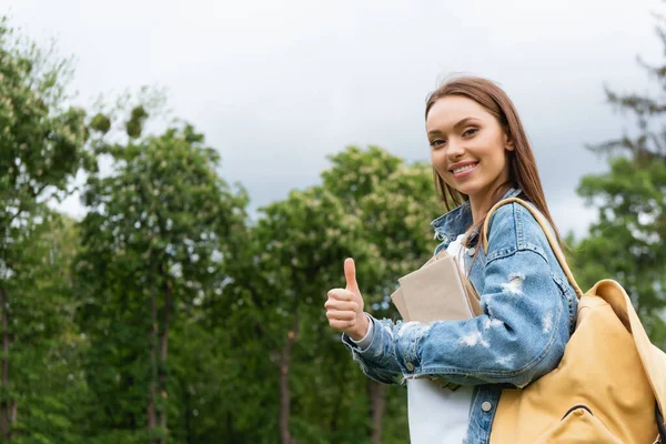 Joyeux et attrayant étudiant regardant la caméra et montrant pouce vers le haut — Photo de stock