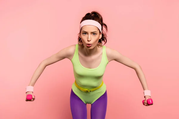 Emotionale Sportlerin trainiert mit Hanteln isoliert auf rosa — Stockfoto