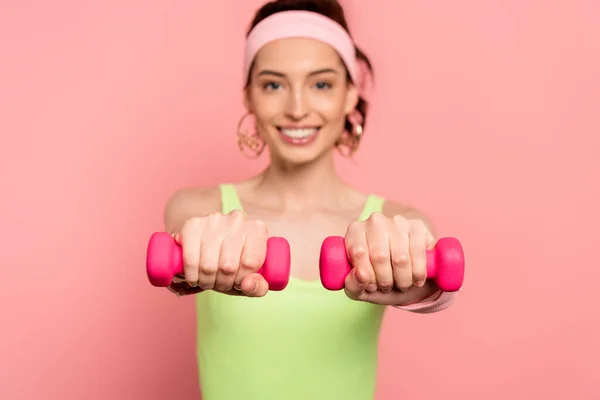 Selective focus of happy sportswoman exercising with dumbbells isolated on pink — Stock Photo