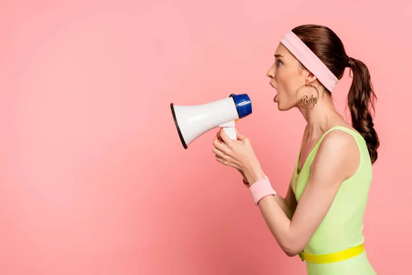 Side view of emotional woman holding loudspeaker and screaming on pink — Stock Photo