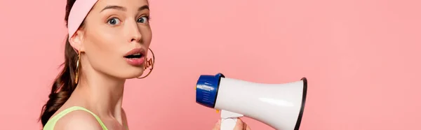 Horizontal concept of surprised woman holding loudspeaker isolated on pink — Stock Photo