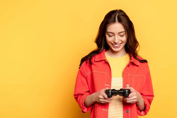 KYIV, UCRANIA - 25 de mayo de 2020: una joven feliz mirando el joystick en amarillo - foto de stock