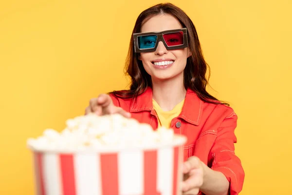 Foyer sélectif de jeune femme heureuse dans des lunettes 3D atteignant pop-corn isolé sur jaune — Photo de stock