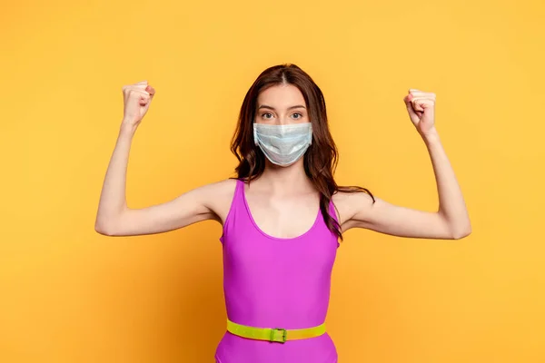 Young woman in medical mask with clenched fists on yellow — Stock Photo