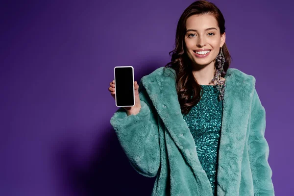Счастливая женщина держит смартфон с экраном на фиолетовом фоне — стоковое фото