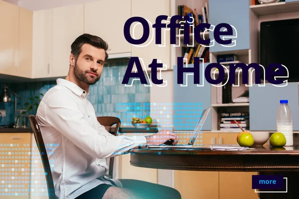 Side view of handsome freelancer in shirt and panties looking at camera near laptop and breakfast on kitchen table, office at home illustration — Stock Photo