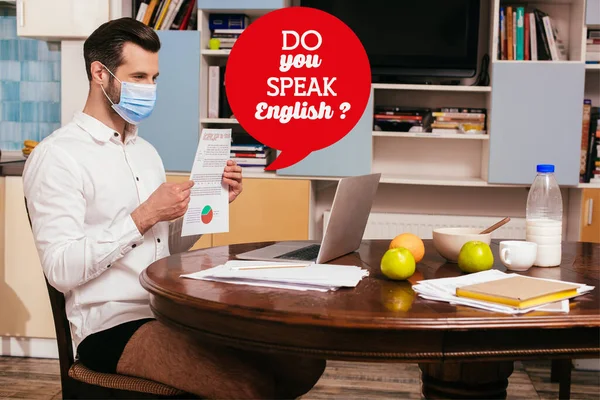 Freelancer in medical mask, shirt and panties holding document while having video chat on laptop near breakfast on table, do you speak English illustration — Stock Photo