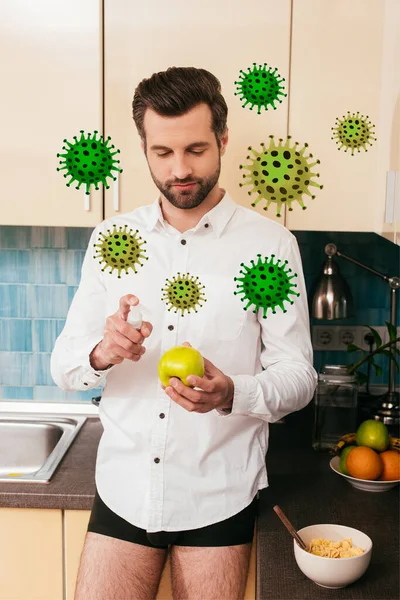 Hombre con camisa y bragas sosteniendo manzana y desinfectante de manos cerca de cereales en la cocina, ilustración de bacterias - foto de stock