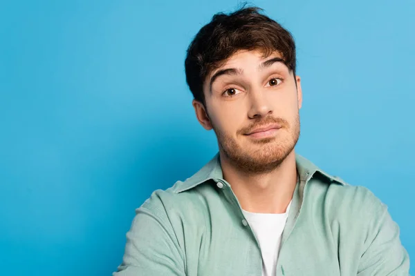 Dreamy young man looking at camera on blue — Stock Photo