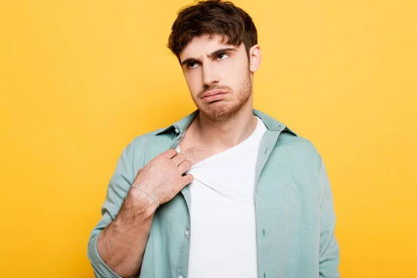 Exhausted young man touching shirt while suffering from heat on yellow — Stock Photo