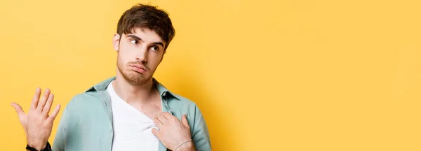 Exhausted young man touching shirt and waving hand while suffering from heat on yellow — Stock Photo