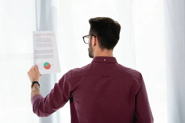 Вид ззаду молодого бізнесмена, який вивчає документ з бізнес-аналітикою — стокове фото