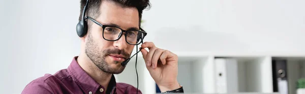 Horizontal image of young businessman in headset having online call — Stock Photo