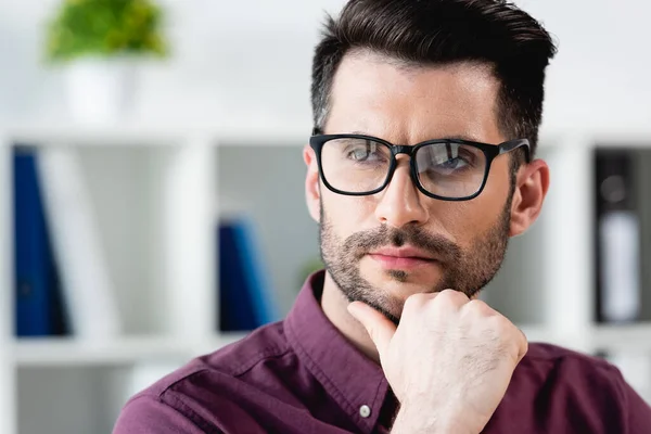 Selbstbewusster, nachdenklicher Geschäftsmann mit Brille, der beim Wegschauen das Kinn berührt — Stockfoto