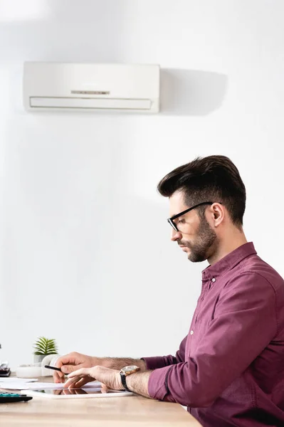 Side view of handsome businessman sitting at workplace under air conditioner — Stock Photo