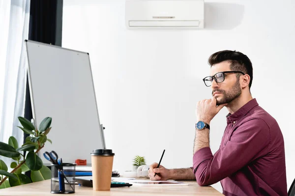 Pensativo hombre de negocios tocando la barbilla, mirando hacia otro lado y sosteniendo el lápiz mientras trabaja cerca de aire acondicionado en la pared — Stock Photo