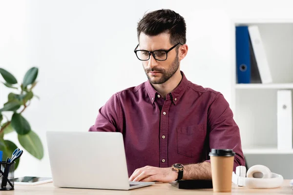Концентрований бізнесмен, який друкує на ноутбуці в офісі — Stock Photo