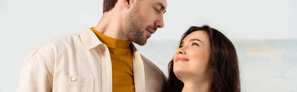 Panoramic shot of handsome man looking at smiling girlfriend at home — Stock Photo