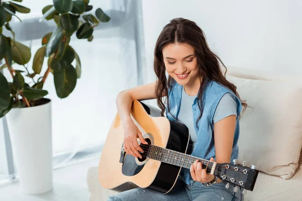 Hermosa mujer sonriente tocando la guitarra acústica en el salón - foto de stock