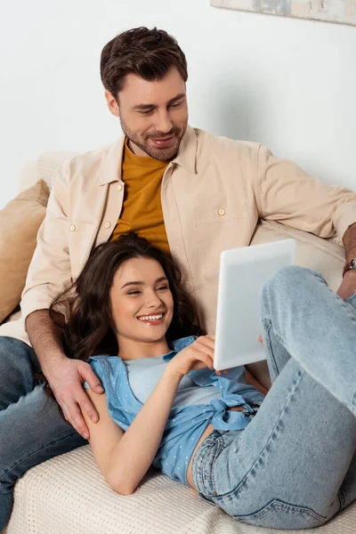 Позитивна пара використовує цифровий планшет на дивані у вітальні — стокове фото