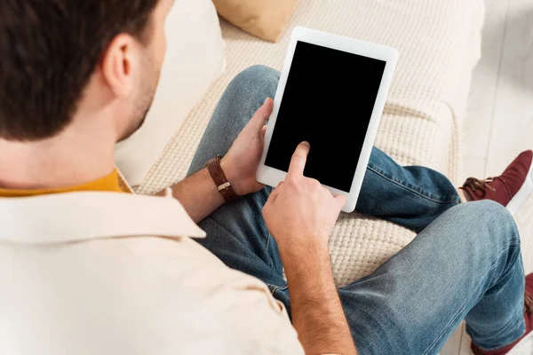 Enfoque selectivo del hombre utilizando tableta digital con pantalla en blanco en el sofá - foto de stock