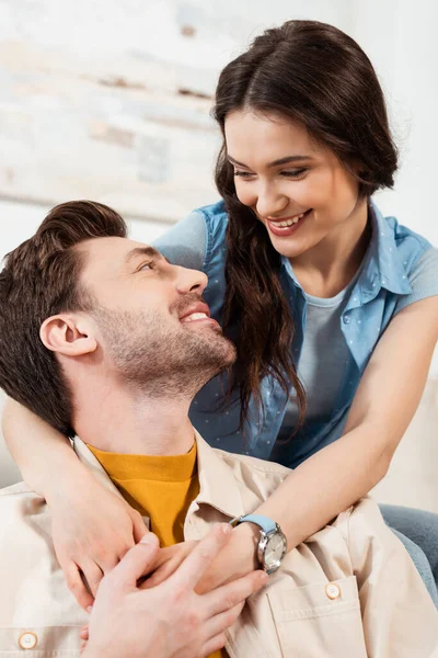 Усміхнена жінка обіймає красивого чоловіка вдома — стокове фото