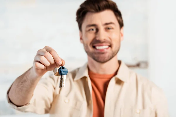 Selective focus of smiling man holding keys of new house — Stock Photo