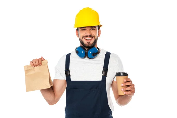 Lavoratore bello che tiene il caffè per andare e sacchetto di carta e sorridente alla macchina fotografica isolata su bianco — Foto stock