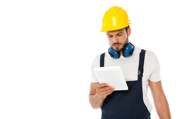 Trabajador en hardhat y defensores del oído sosteniendo tableta digital aislada en blanco - foto de stock