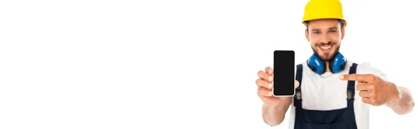 Panoramaausschnitt eines lächelnden Heimwerkers, der mit dem Finger auf ein Smartphone zeigt, mit leerem Bildschirm, isoliert auf Weiß — Stockfoto