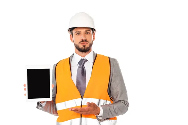 Ingeniero en traje y casco de seguridad apuntando con la mano a la tableta digital aislada en blanco - foto de stock