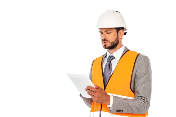 Ingeniero guapo en traje y chaleco de seguridad usando tableta digital aislada en blanco - foto de stock