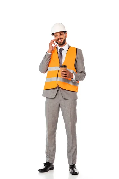 Усміхнений інженер розмовляє на смартфоні і тримає одноразову чашку на білому тлі — стокове фото