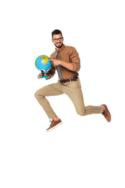 Positive teacher pointing with finger at globe while jumping isolated on white — Stock Photo