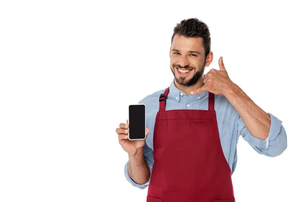 Lächelnder Kellner gestikuliert und hält Smartphone mit leerem Bildschirm isoliert auf weiß — Stockfoto