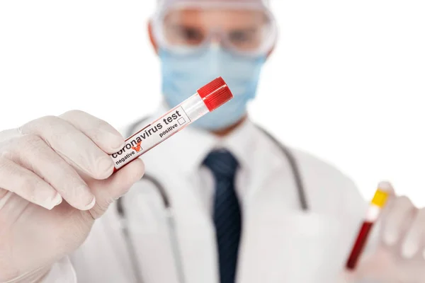 Concentration sélective du médecin dans le masque médical montrant tube à essai avec échantillon de sang et lettrage coronavirus isolé sur blanc — Photo de stock