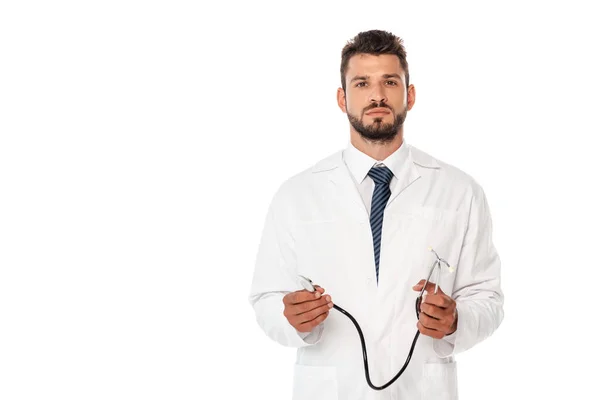 Médico bonito olhando para a câmera e segurando estetoscópio isolado no branco — Fotografia de Stock