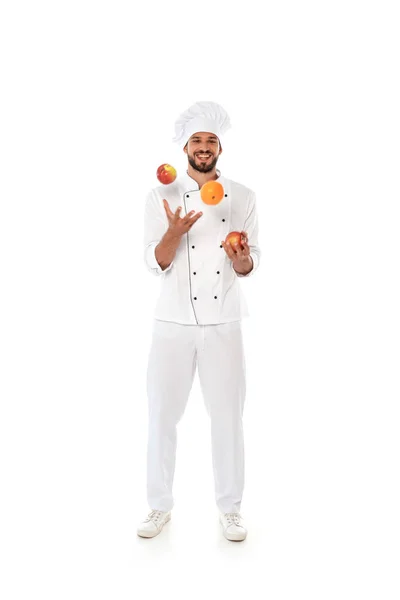 Smiling chef juggling fresh fruits on white background — Stock Photo