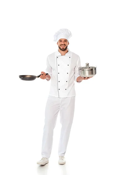 Bonito chef sorridente segurando frigideira e pan no fundo branco — Fotografia de Stock