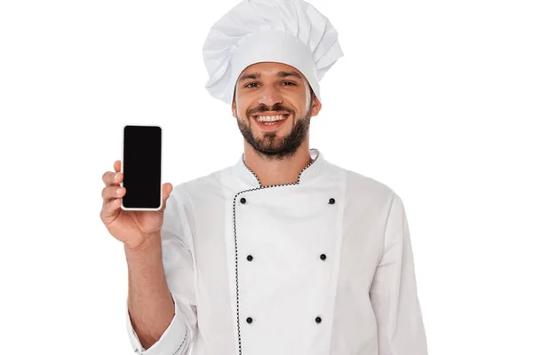 Chef sorridente in uniforme che mostra smartphone con schermo bianco isolato su bianco — Foto stock