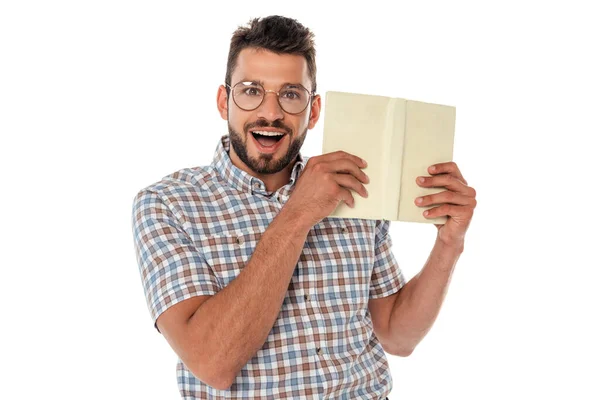 Nerd alegre en anteojos sosteniendo libro abierto aislado en blanco - foto de stock