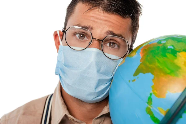 Focus selettivo di nerd in maschera medica tenendo globo e guardando la fotocamera isolata su bianco — Foto stock
