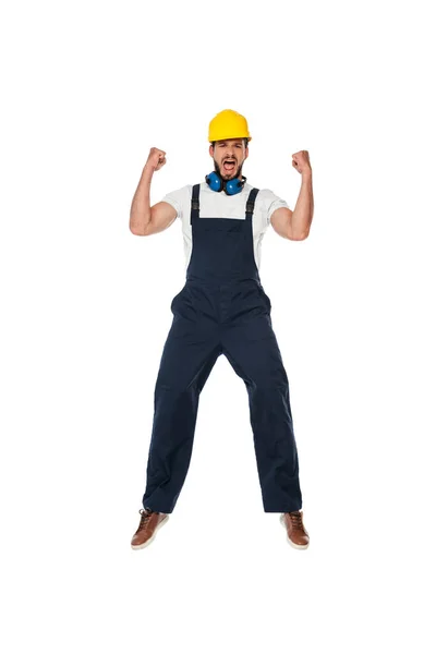 Emocionado constructor en ropa de trabajo y hardhat mostrando sí gesto aislado en blanco - foto de stock
