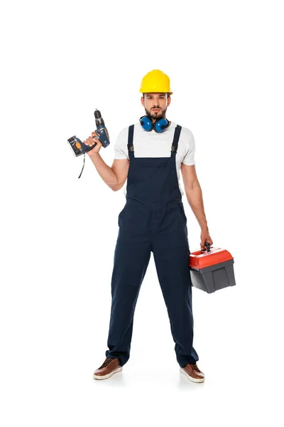 Trabalhador bonito em uniforme e hardhat segurando chave de fenda elétrica e caixa de ferramentas no fundo branco — Fotografia de Stock