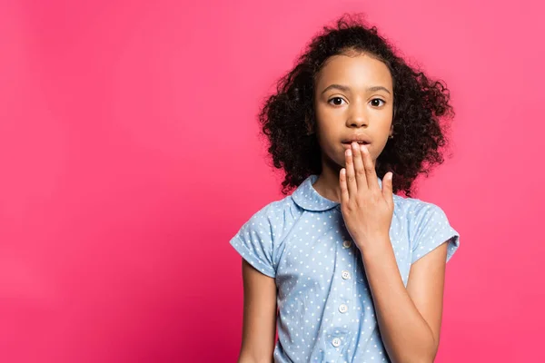Süße lockige afrikanische amerikanische Kind bedeckt Mund isoliert auf rosa — Stockfoto