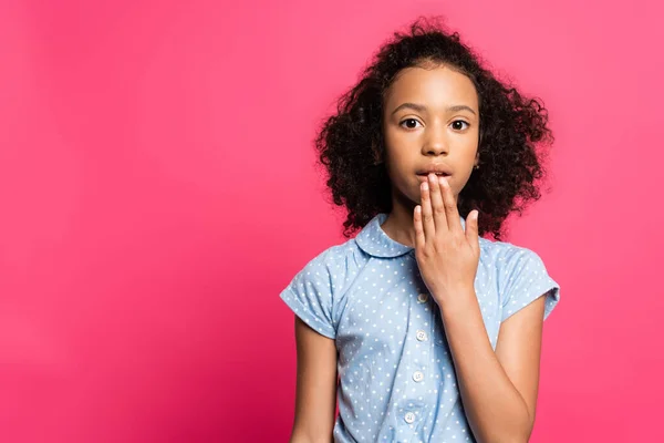 Mignon frisé afro-américain enfant couvrant bouche isolé sur rose — Photo de stock