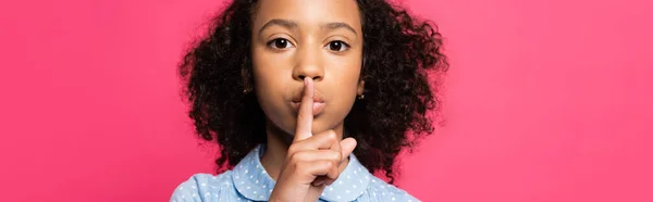 Süße lockige afrikanisch-amerikanische Kind zeigt shh Zeichen isoliert auf rosa, Panorama-Aufnahme — Stockfoto